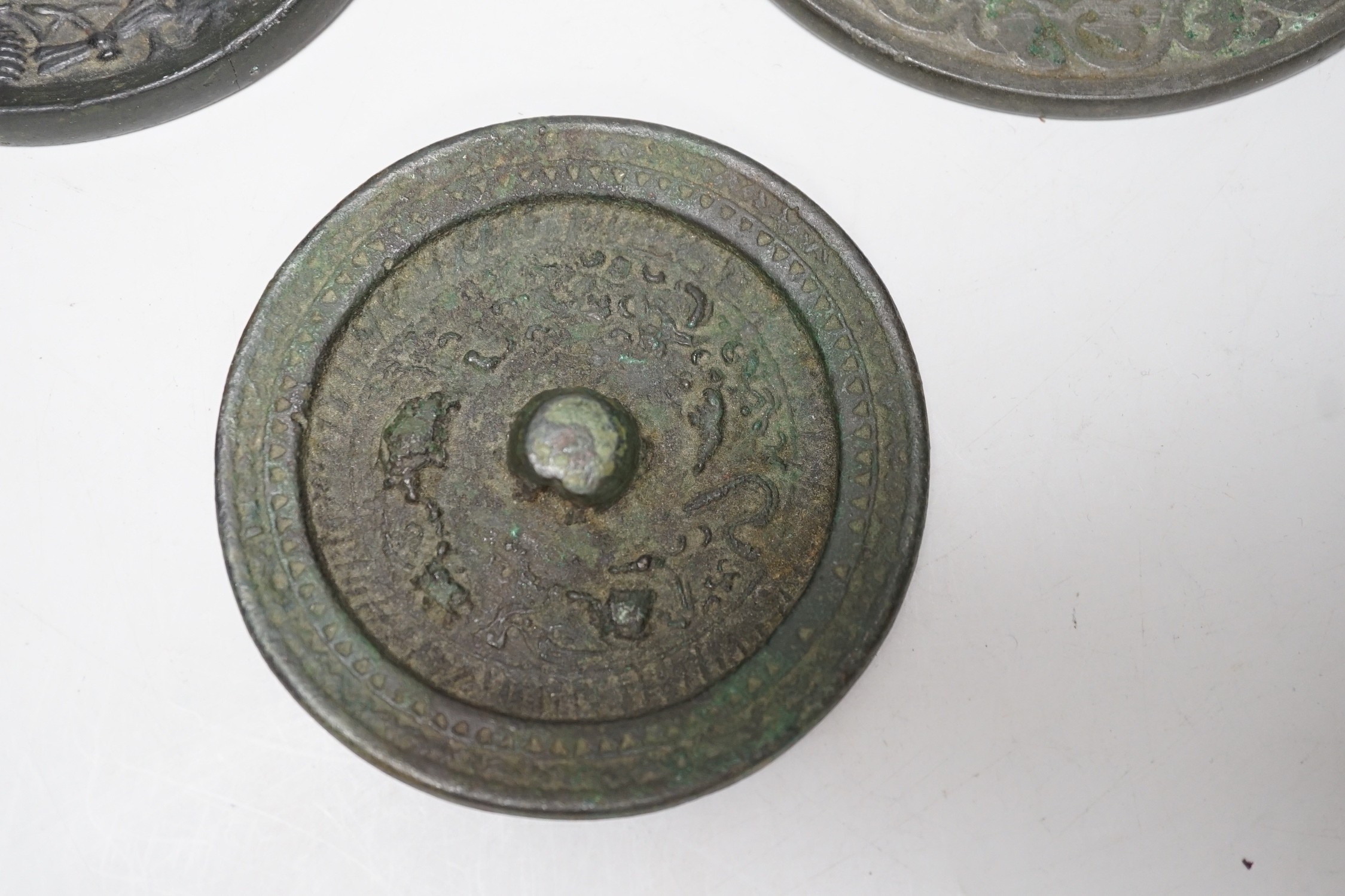 A group of six Chinese archaic bronze mirrors, including two Han dynasty TLV mirrors, and a Tang dynasty squirrel and vine small mirror, five corroded, largest 14cm diameter